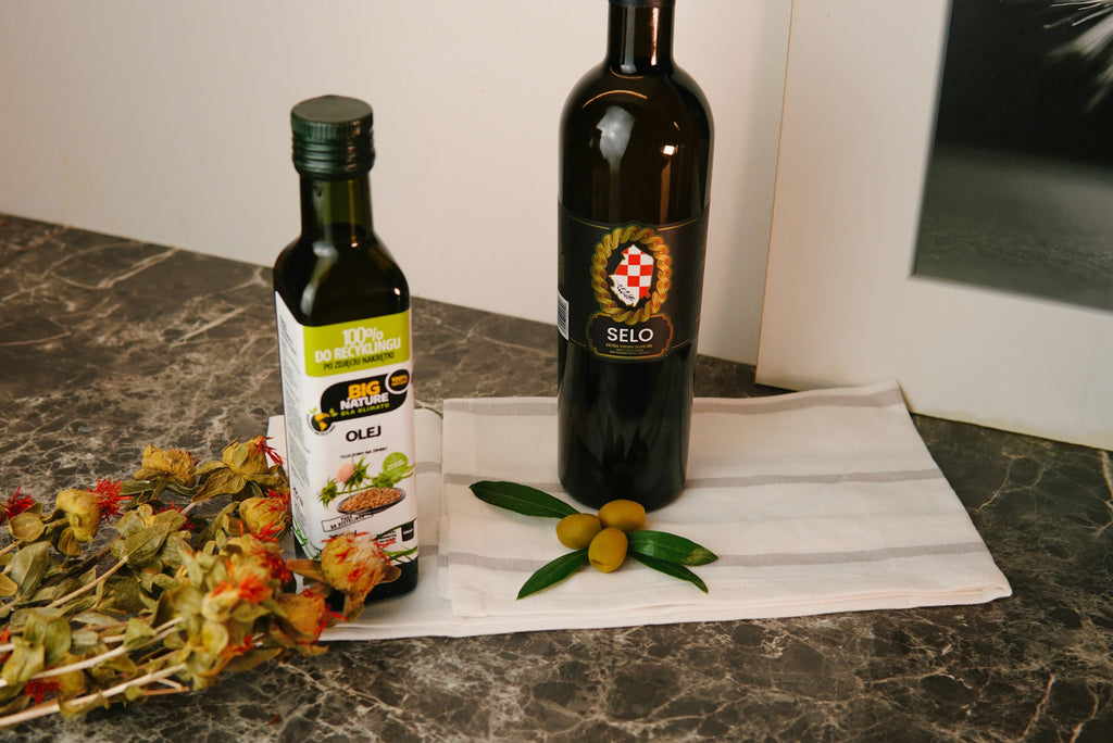 A bottle of safflower oil on a marble table, surrounded by vibrant safflower flowers, signifying its plant-based origins.